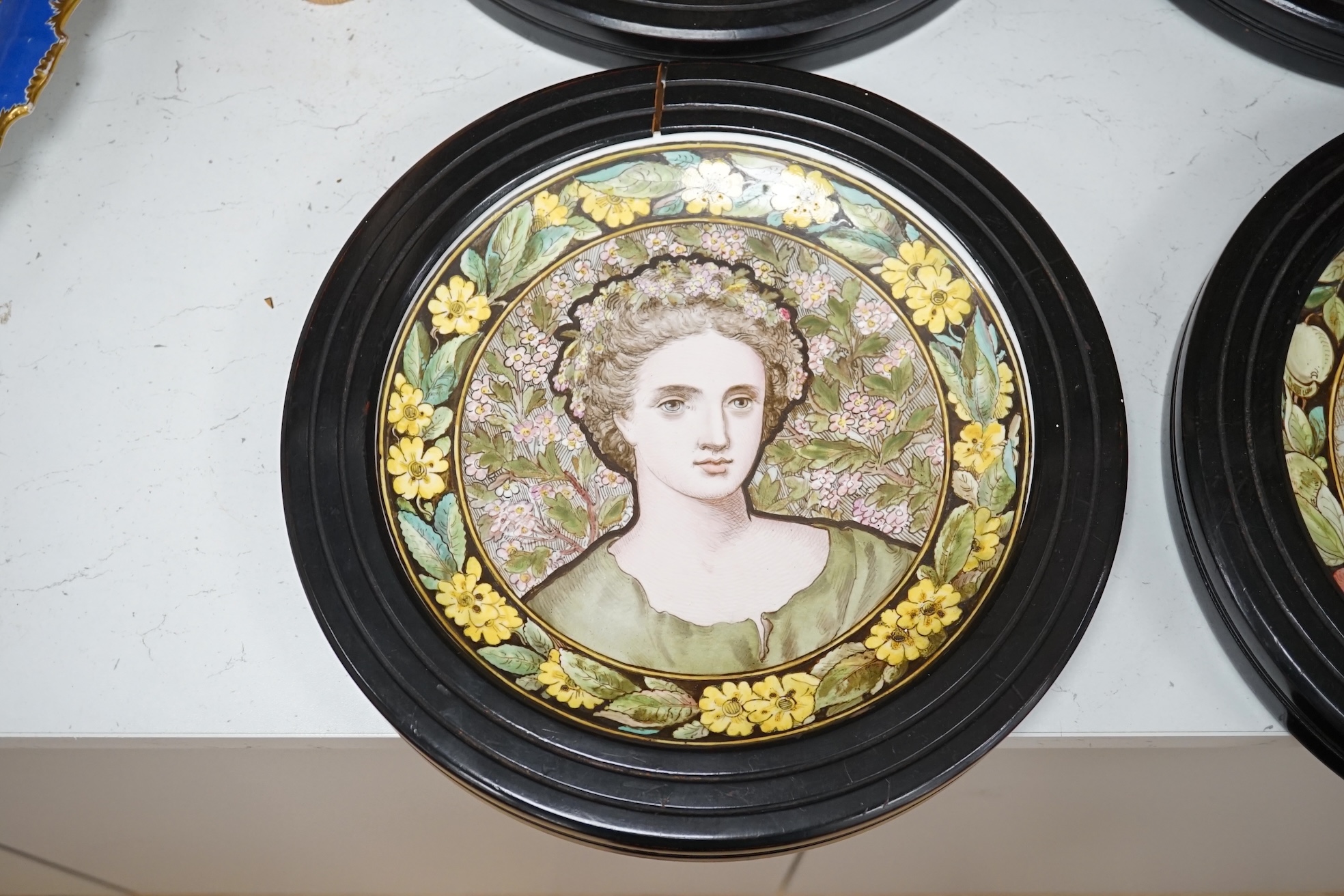 A set of four Copeland Spode Aesthetic period, outside decorated four seasons portrait plates, circa 1880, housed in ebonised wood frames, overall 31cm in diameter. Condition - fair, three frames cracked